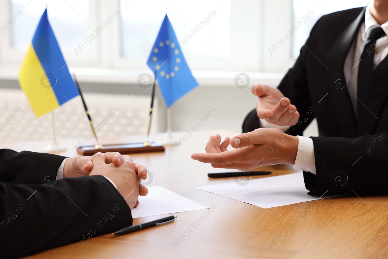 Photo of Diplomats negotiating during meeting at wooden table indoors, closeup