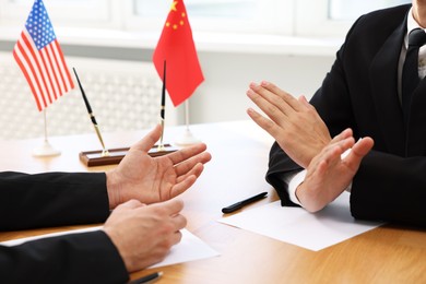 Diplomats negotiating during meeting at wooden table indoors, closeup