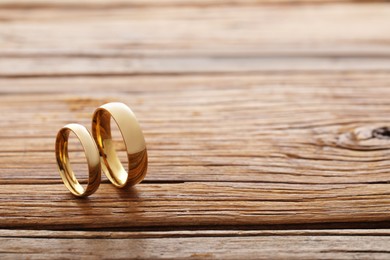 Beautiful golden wedding rings on wooden background, space for text