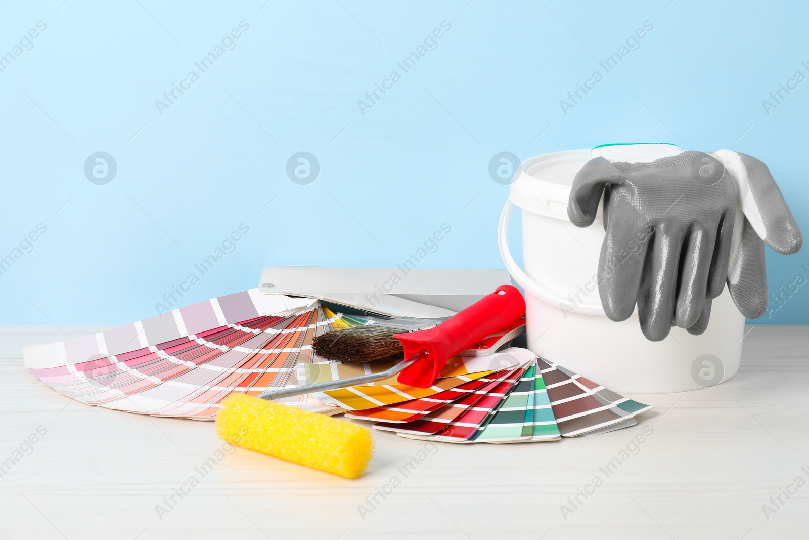 Photo of Different painter's tools on white wooden table. Decorating and design