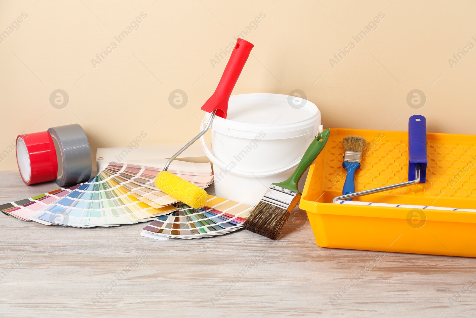 Photo of Different painter's tools on light wooden table. Decorating and design