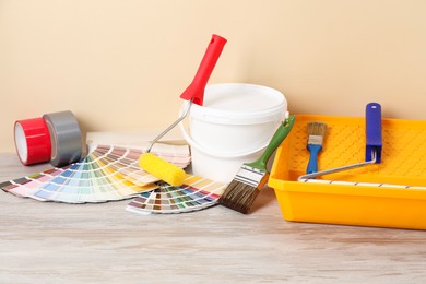 Photo of Different painter's tools on light wooden table. Decorating and design