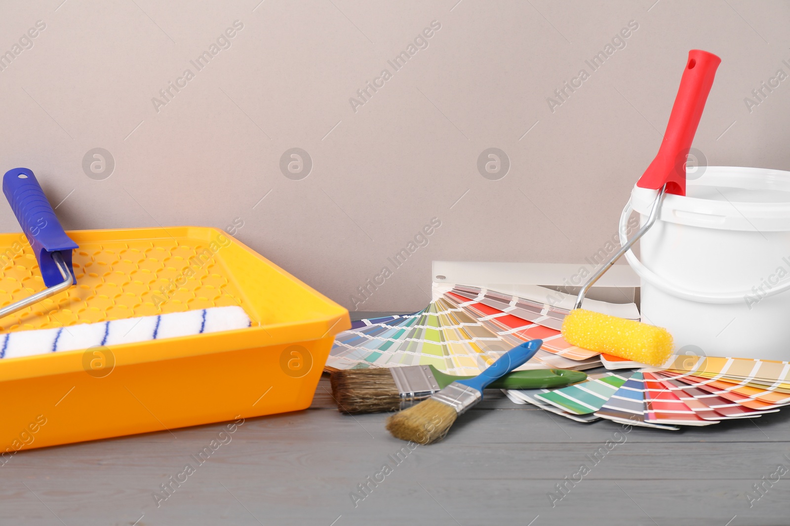 Photo of Different painter's tools on grey wooden table. Decorating and design