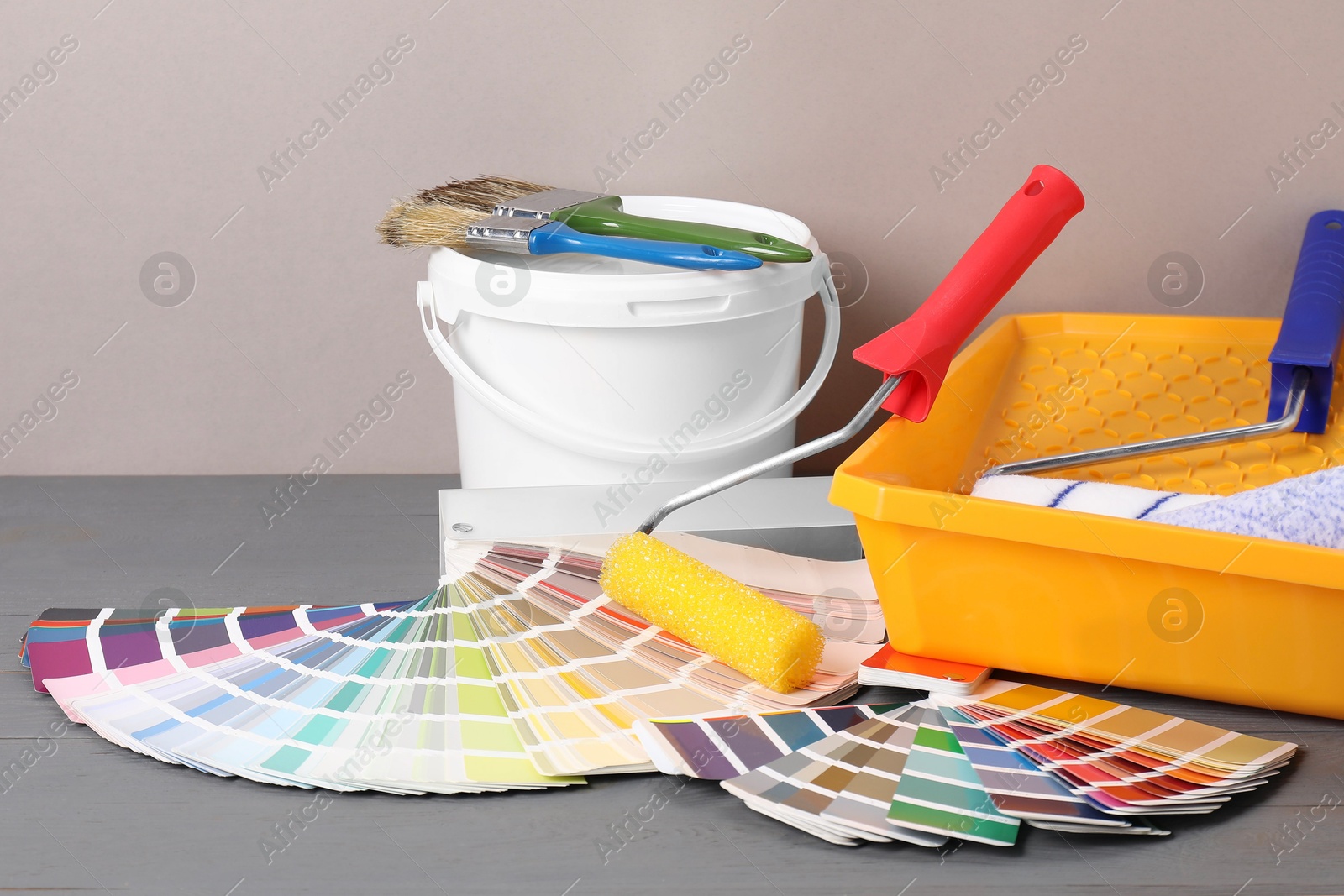 Photo of Different painter's tools on grey wooden table. Decorating and design