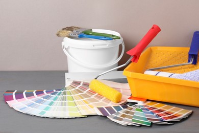 Photo of Different painter's tools on grey wooden table. Decorating and design