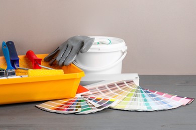 Photo of Different painter's tools on grey wooden table. Decorating and design