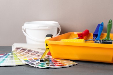 Photo of Different painter's tools on grey wooden table. Decorating and design