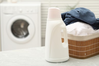 Photo of Detergent and basket with laundry on light table indoors. Space for text