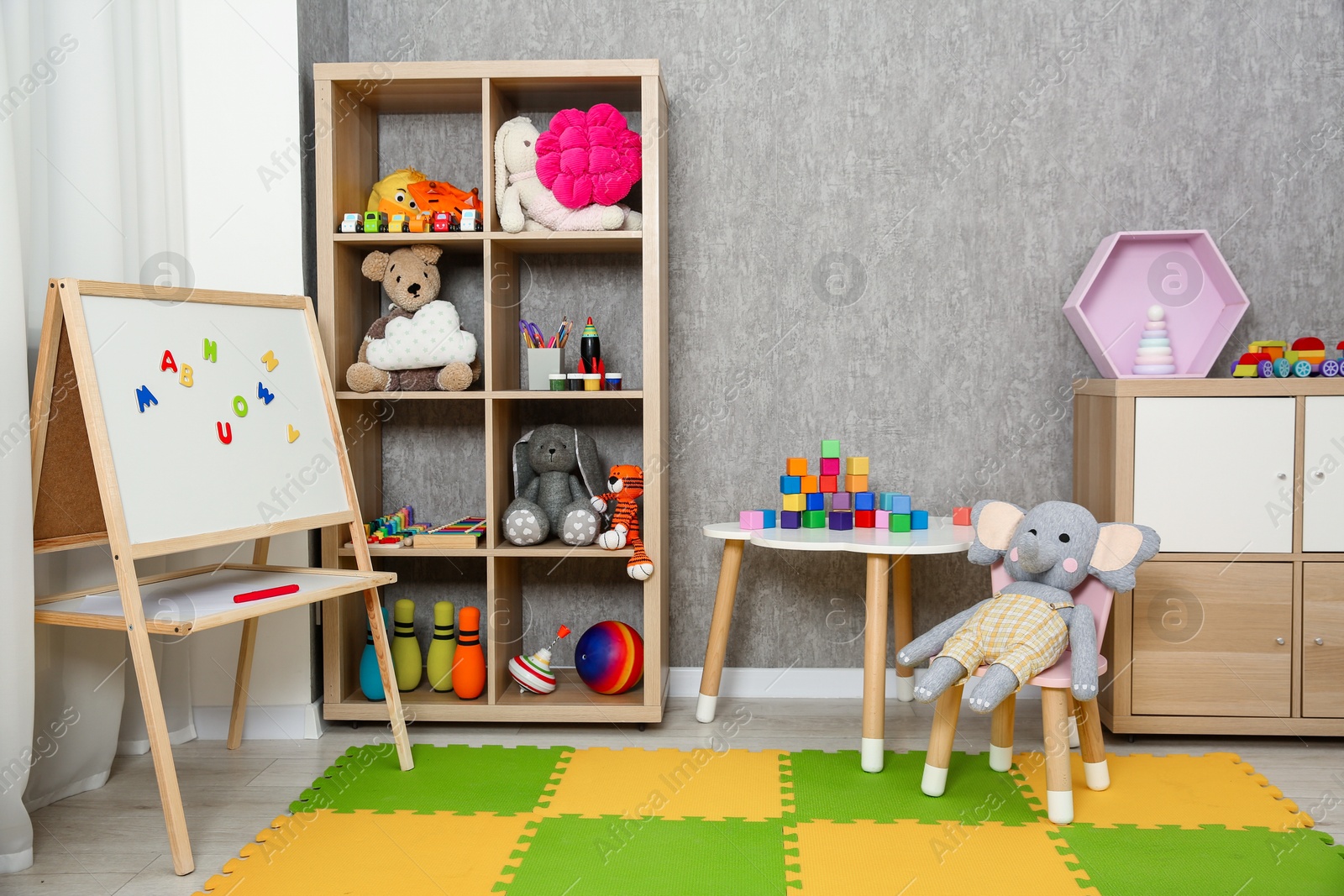 Photo of Beautiful kid's room interior with toys, whiteboard and stylish furniture