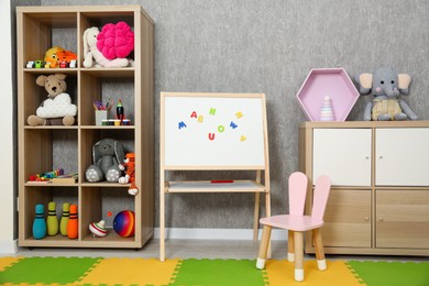 Photo of Beautiful kid's room interior with toys, whiteboard and stylish furniture