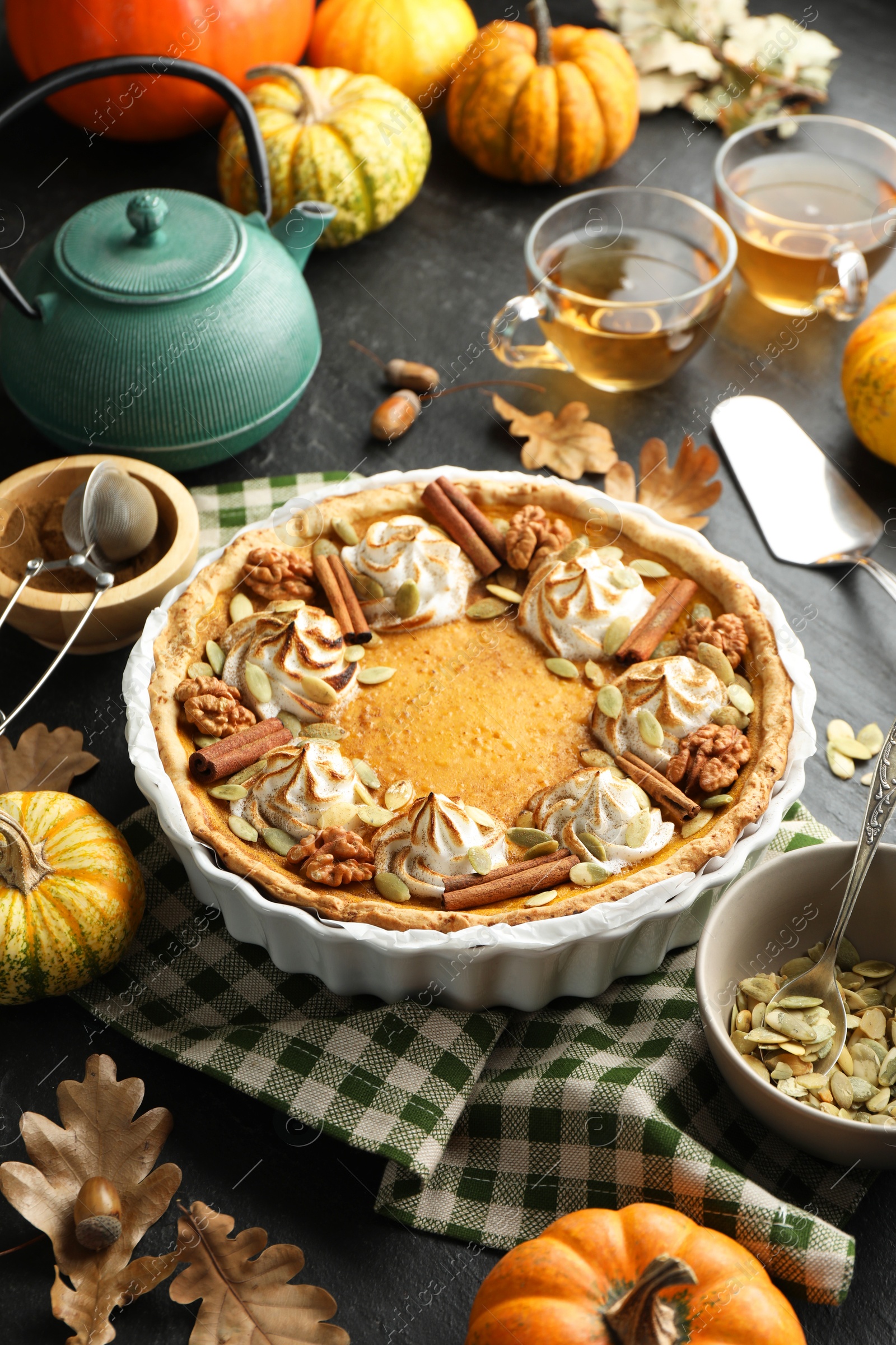 Photo of Homemade pumpkin pie with whipped cream, seeds and cinnamon on grey table