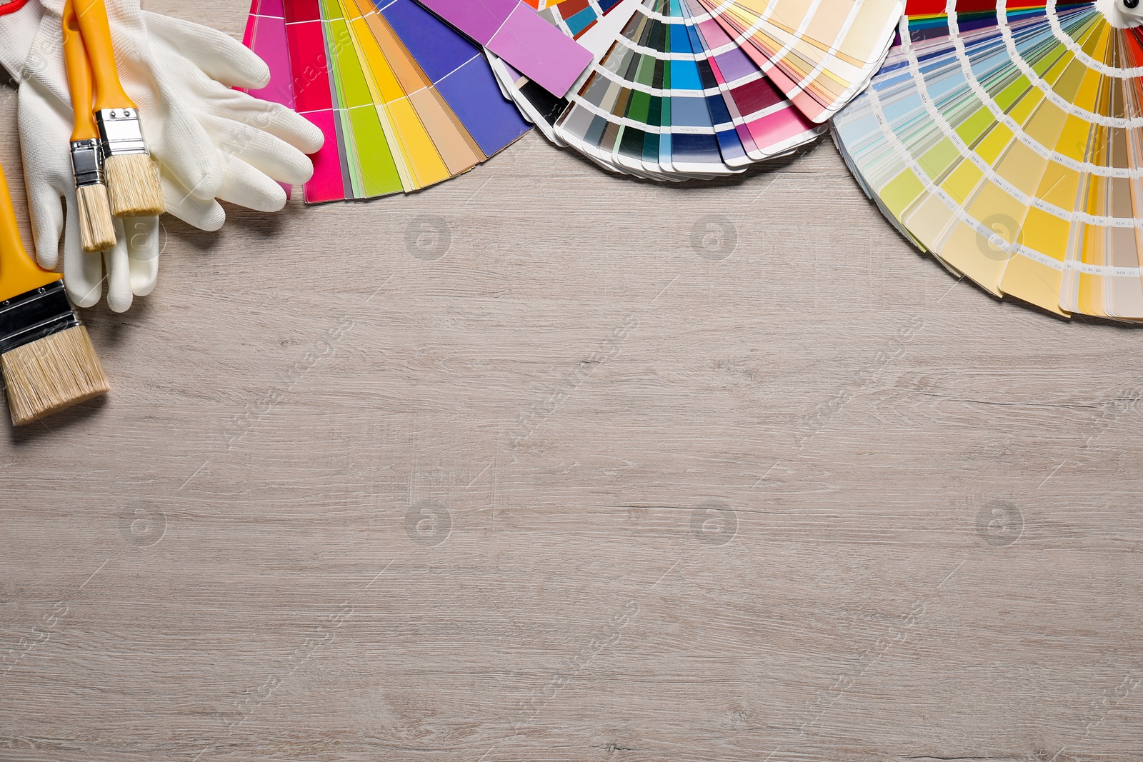 Photo of Different painter's tools on wooden table, flat lay with space for text. Decorating and design