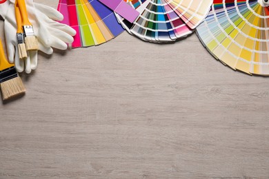 Photo of Different painter's tools on wooden table, flat lay with space for text. Decorating and design