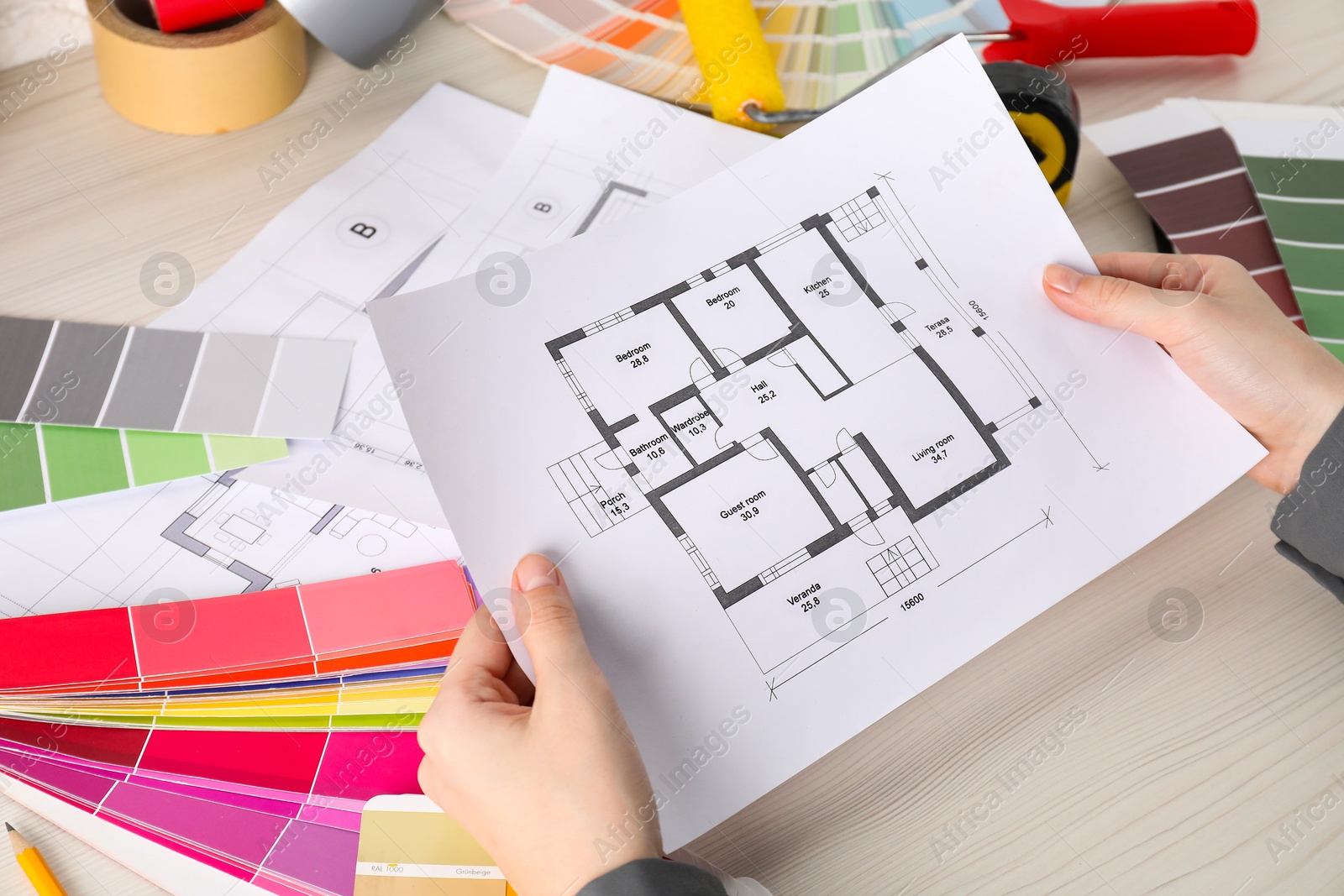 Photo of Designer working with house plan at white wooden table, closeup