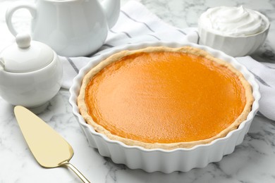 Tasty homemade pumpkin pie and server on white marble table, closeup