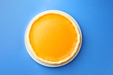 Photo of Tasty homemade pumpkin pie on blue background, top view