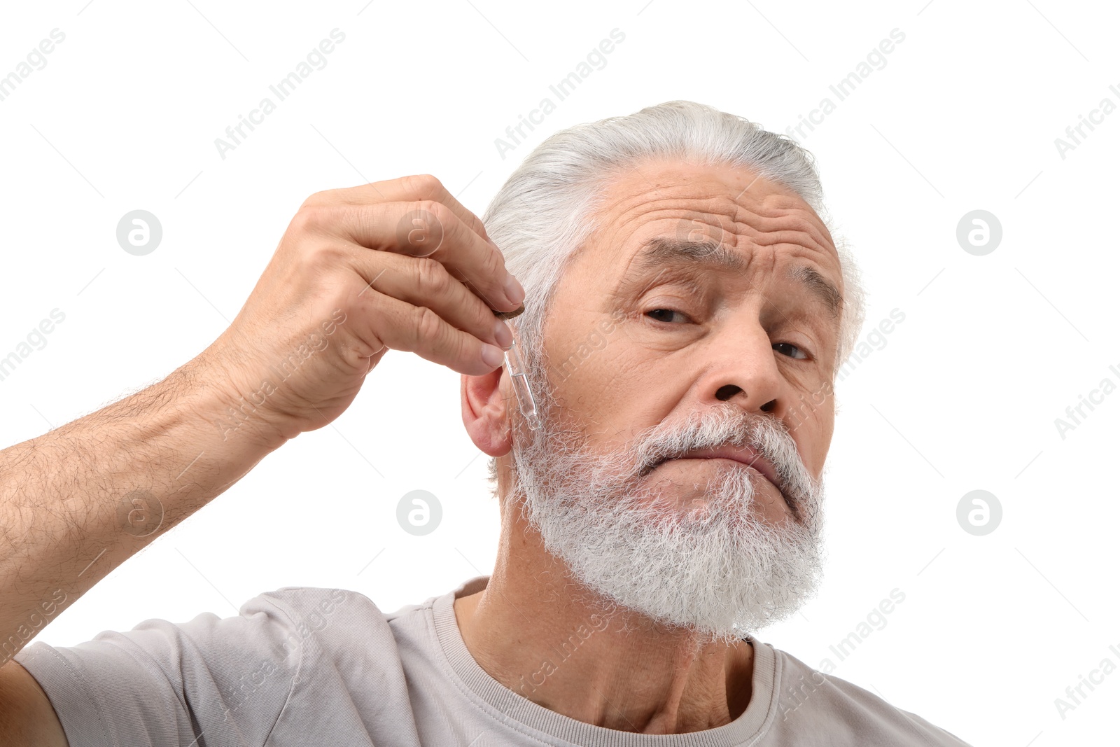 Photo of Senior man applying serum onto his beard on white background