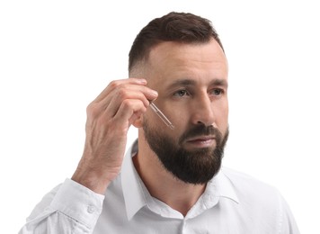 Man applying serum onto his beard on white background