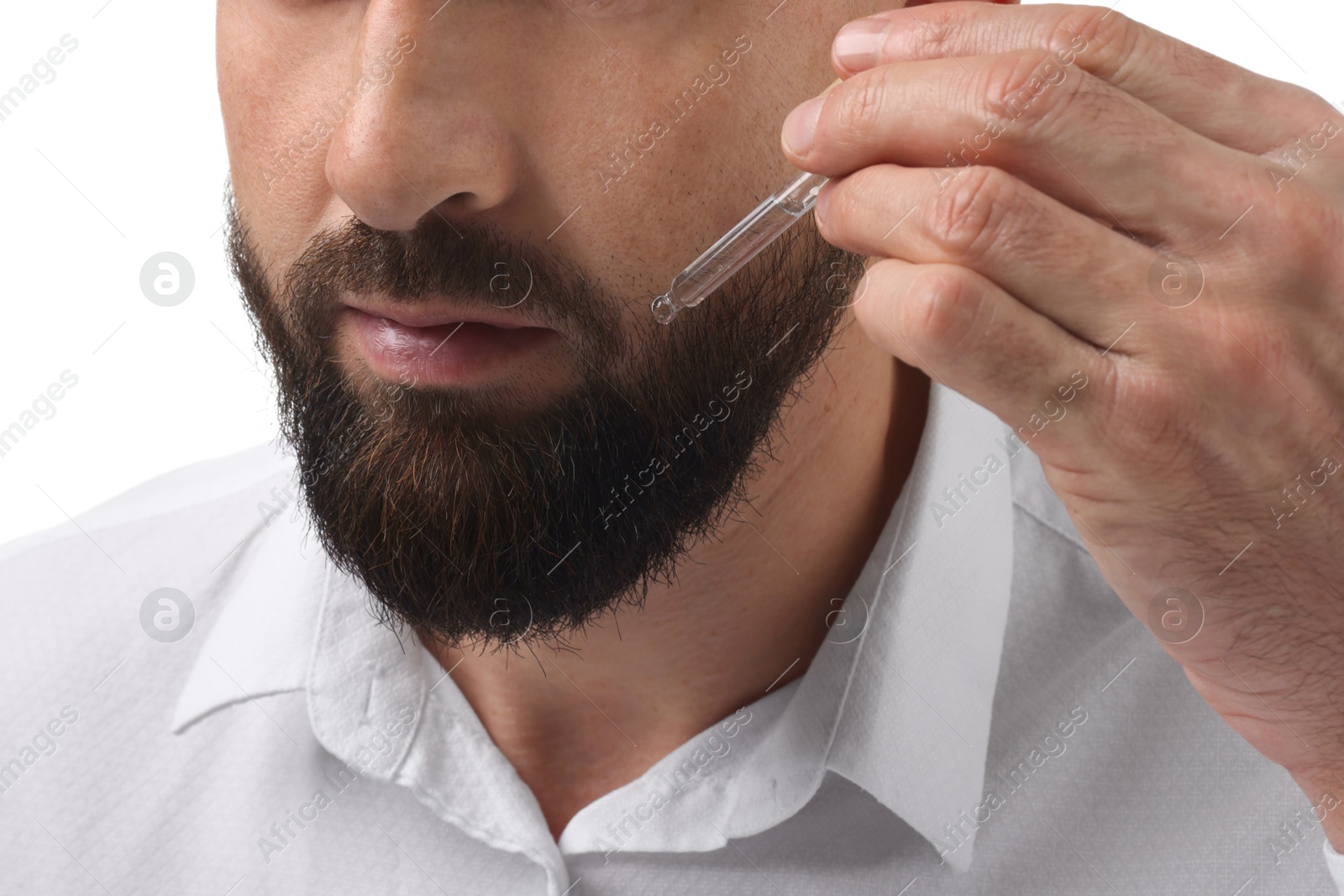 Photo of Man applying serum onto his beard on white background, closeup