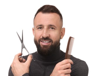 Bearded man holding comb and scissors on white background