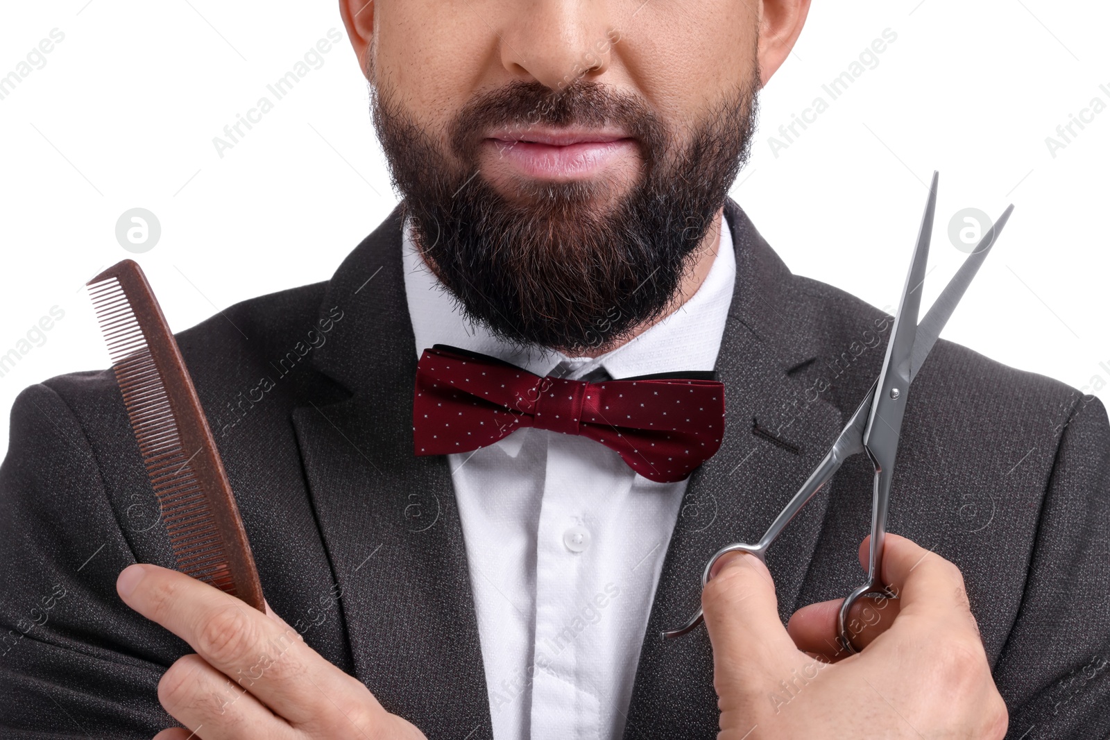 Photo of Bearded man holding comb and scissors on white background, closeup