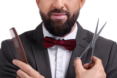 Bearded man holding comb and scissors on white background, closeup