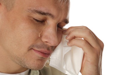 Photo of Crying man wiping tears with tissue on white background