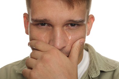 Distressed young man crying on white background