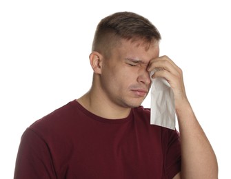 Crying man wiping tears with tissue on white background