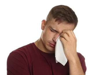 Photo of Crying man wiping tears with tissue on white background