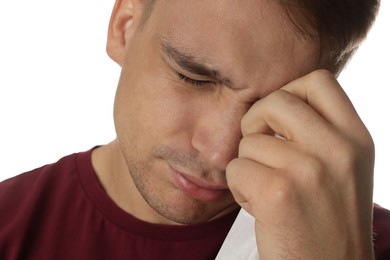 Crying man wiping tears with tissue on white background