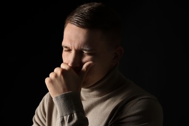 Distressed young man crying on black background