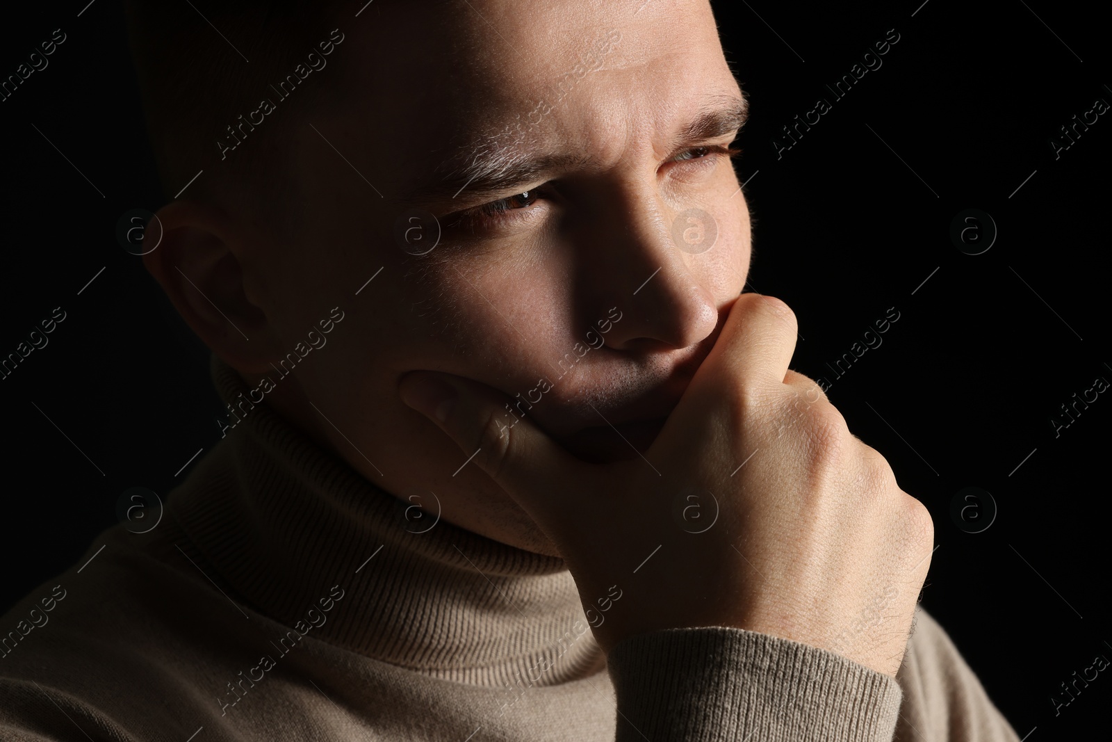 Photo of Distressed young man crying on black background, closeup