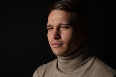 Distressed young man crying on black background