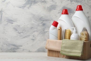 Photo of Eco-friendly cleaning products and supplies in crate on light wooden table, space for text