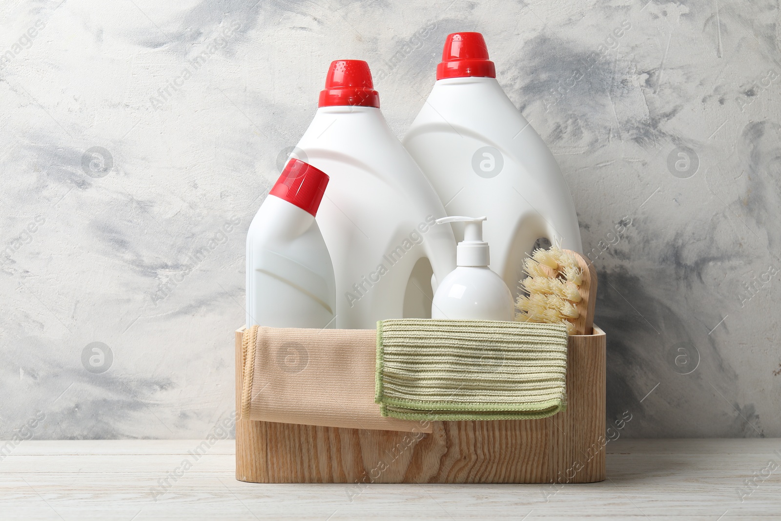 Photo of Eco-friendly cleaning products and supplies in crate on light wooden table