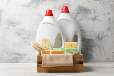 Photo of Eco-friendly cleaning products and supplies in crate on light wooden table