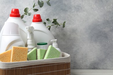 Photo of Eco-friendly cleaning products, supplies and eucalyptus branches in wicker basket on table, space for text