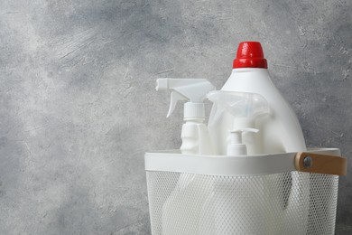 Photo of Different cleaning products in basket against grey background, space for text