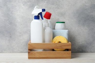 Photo of Eco-friendly cleaning products and supplies in crate on light wooden table