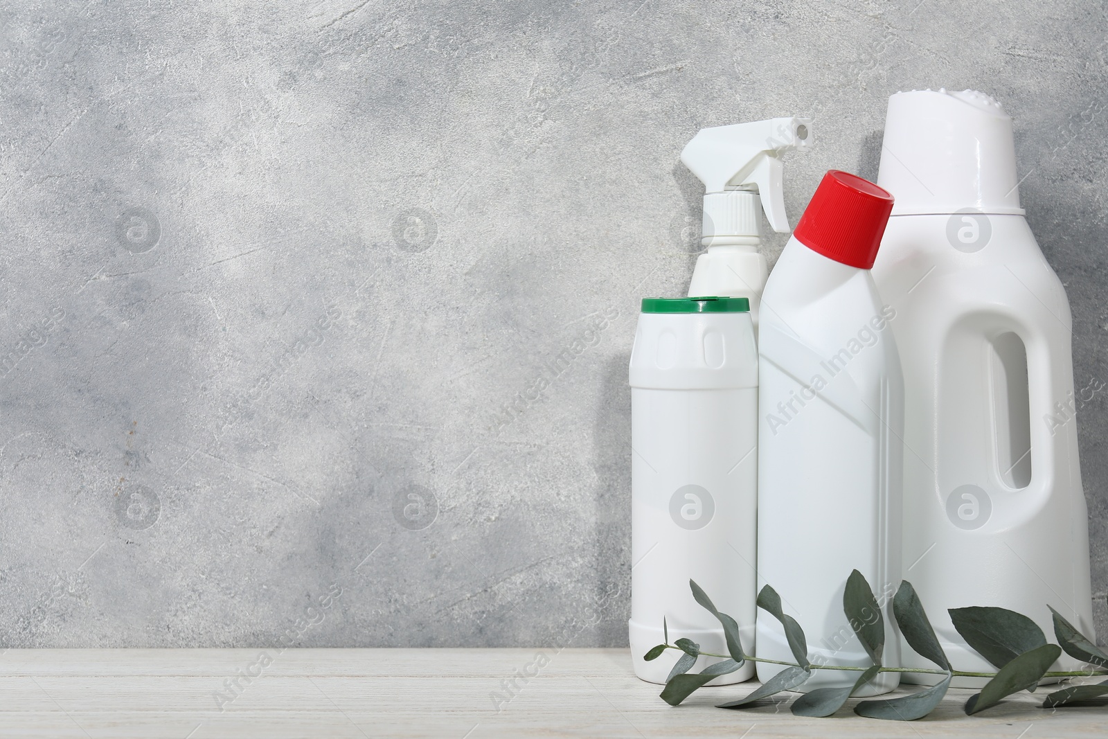 Photo of Eco-friendly cleaning products and eucalyptus branch on light wooden table, space for text