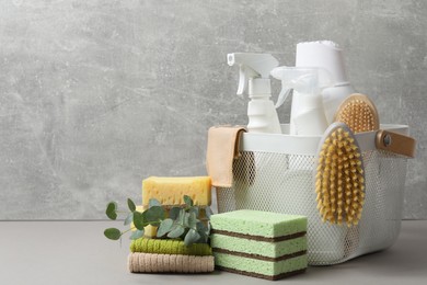 Photo of Eco-friendly cleaning products, supplies and eucalyptus branches on grey table, space for text