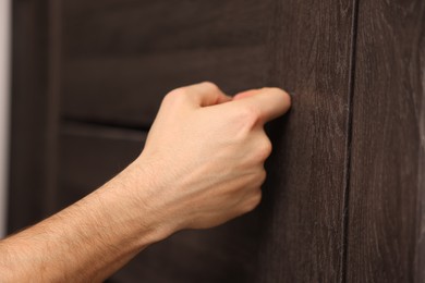 Photo of Man knocking on door to his friends apartment, closeup