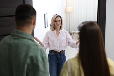 Photo of Happy woman welcoming friends to her apartment