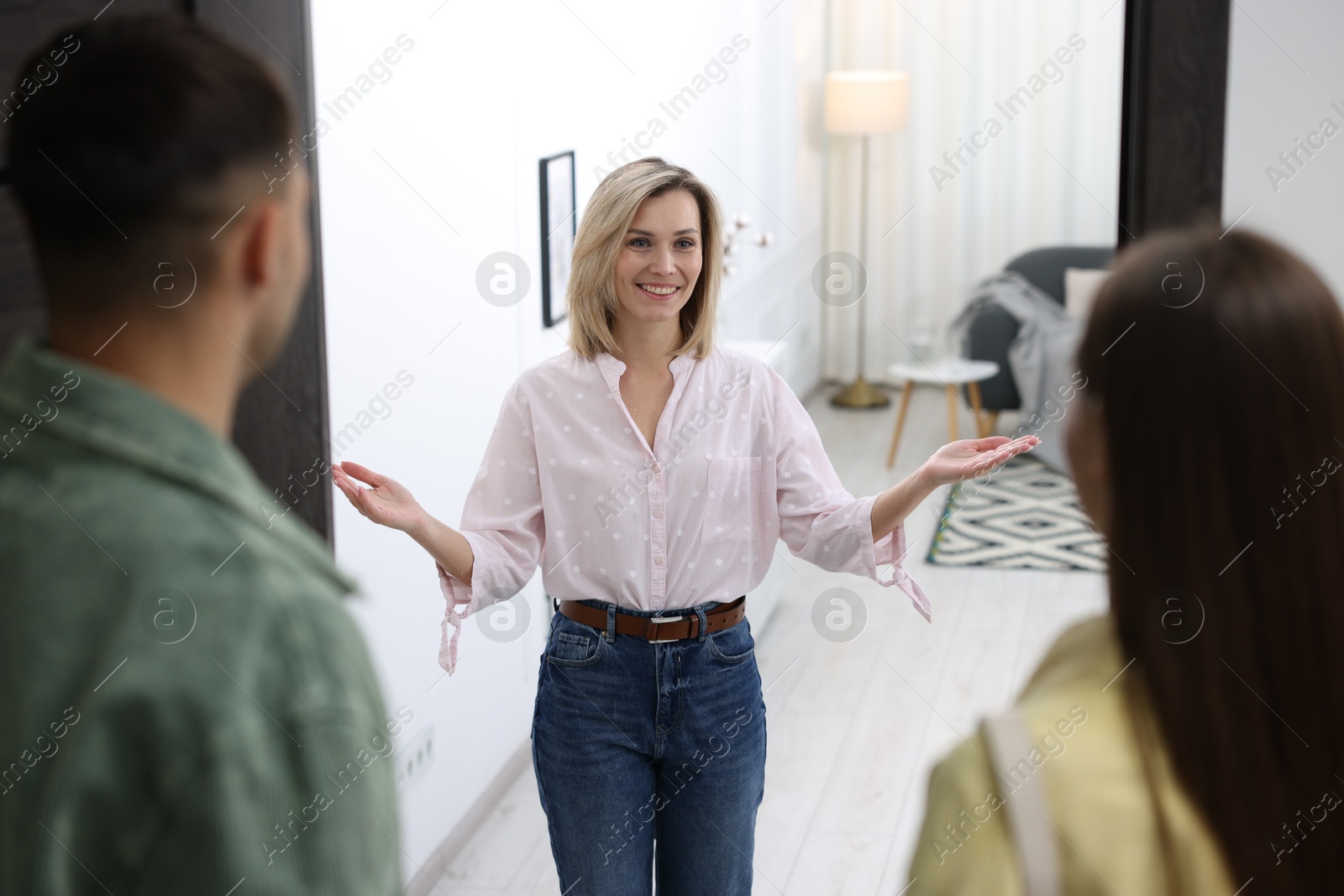 Photo of Happy woman welcoming friends to her apartment