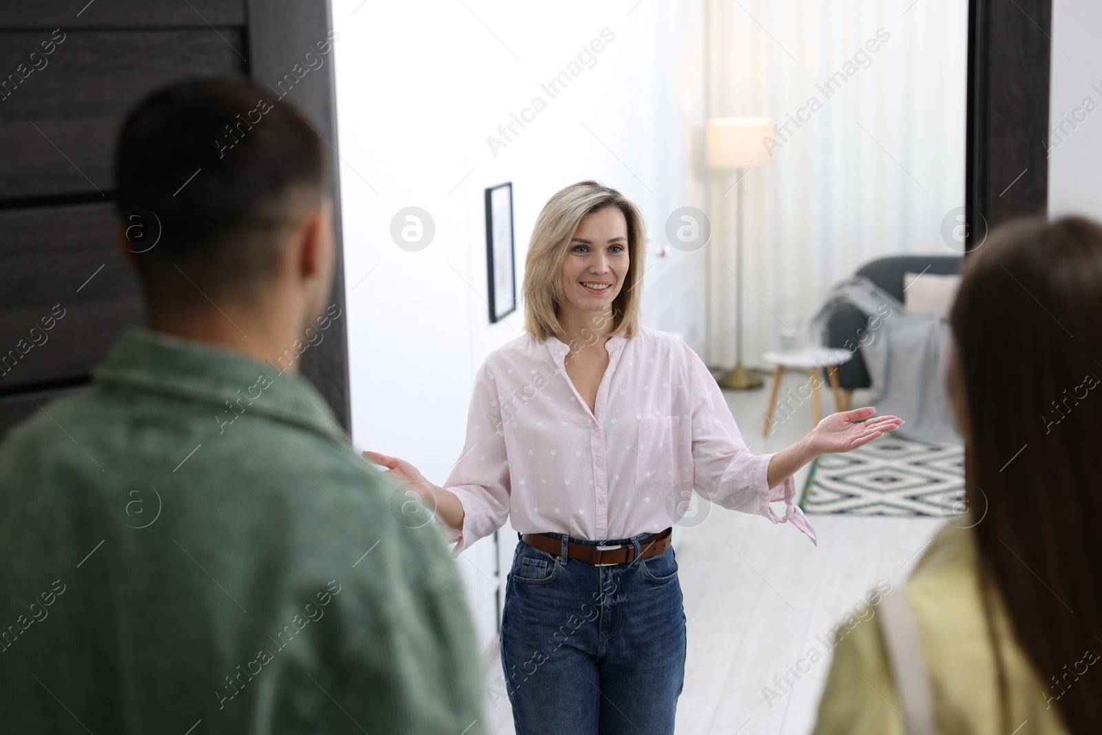 Photo of Happy woman welcoming friends to her apartment