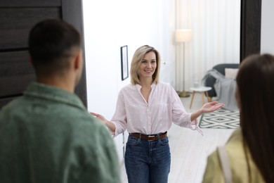 Photo of Happy woman welcoming friends to her apartment