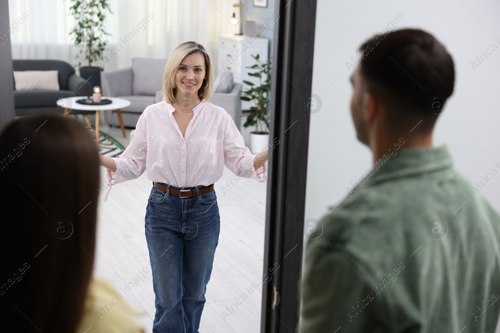 Photo of Happy woman welcoming friends to her apartment