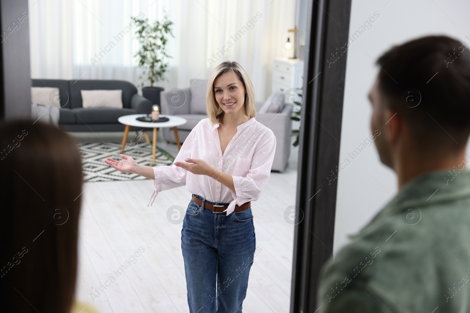 Photo of Happy woman welcoming friends to her apartment