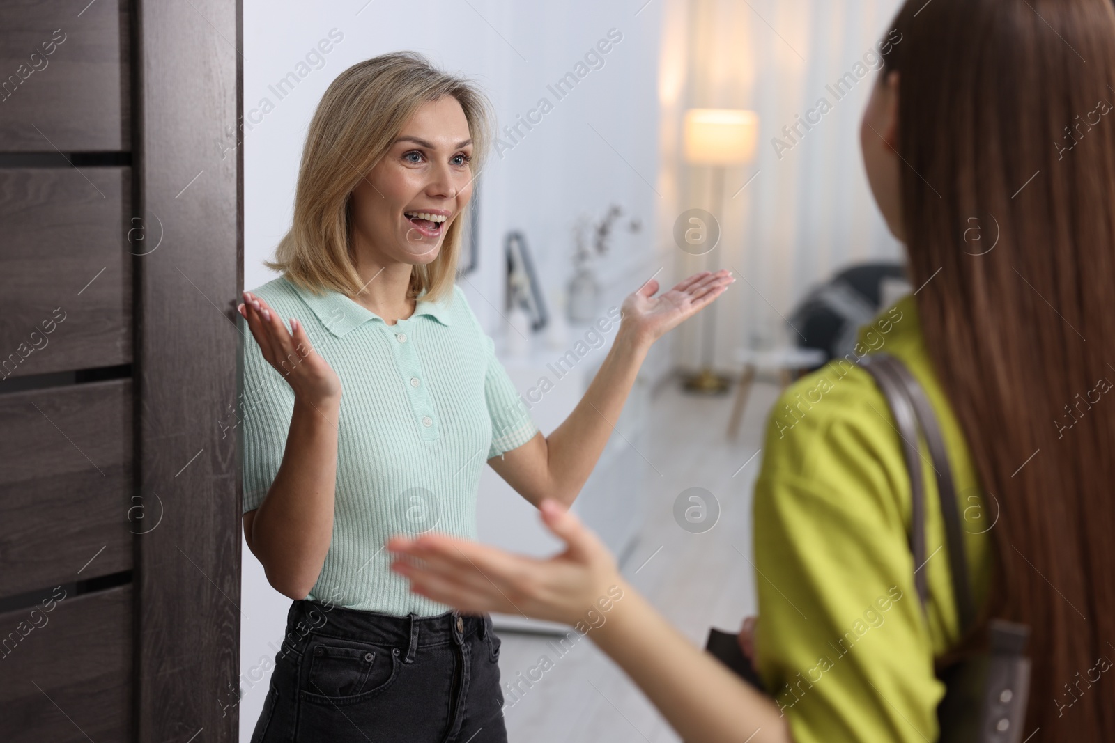 Photo of Cheerful woman welcoming neighbor to her apartment